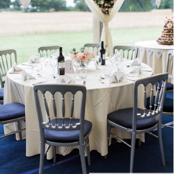 Silver spindle back banqueting chairs with blue seat pads at a blue & ivory themed wedding